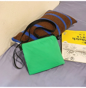 Sac bandoulière minimaliste en nylon vert pour voyage sur fond de surface bleue