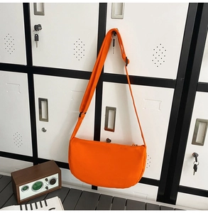 Detailed view of an orange crescent crossbody bag made of nylon fabric with wide strap