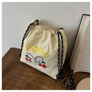 Detail der Kirschstickerei und des Poppy-Schriftzugs auf der beigen Kordelzugtasche