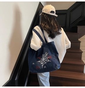 Dunkelblaue Denim-Tasche mit weißem Spinnennetz und roter Spinnenstickerei am Rücken