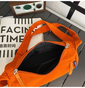 Detail of vibrant orange nylon crossbody bag showing inner pocket and black lining