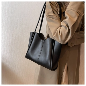 Classic black tote bag in matte synthetic leather styled with a khaki trench coat