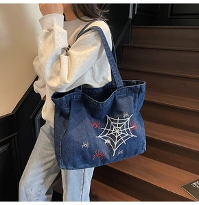Close-up of gothic spider web embroidery on vintage dark blue denim tote bag for women