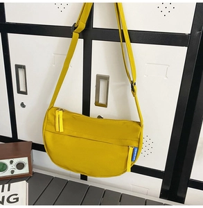 Detailed shot of yellow crescent nylon crossbody bag with strap and front zipper