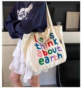 Primer plano del bolso tote de lona crema con bordado colorido let's think about earth