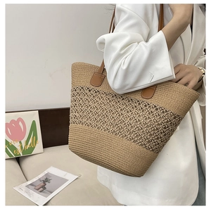 Detail of woven straw tote bag with brown leather handles and hollowed patterns