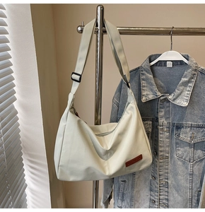 Detail of cream large tote bag with adjustable strap and brand logo on hanger