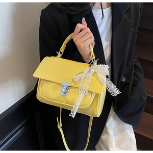 Detail of yellow PU leather bag with white lace pearl bow and silver clasp