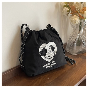 Detail der Nylon-Kordelzugtasche mit Herz-Kuh-Stickerei und geflochtenem Schultergurt
