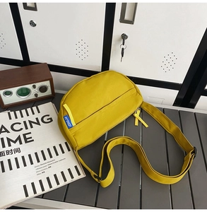 Detail of bright yellow canvas crossbody bag with blue label on a vintage background