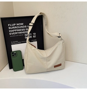 Close-up of cream canvas tote bag with adjustable strap and leather logo patch detail