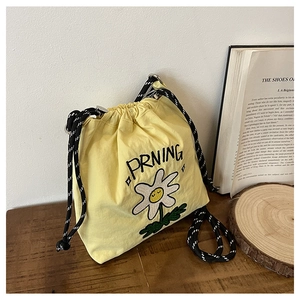 Detail der gelben Nylon-Beuteltasche mit Gänseblümchen-Stickerei und Webriemen