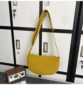 Detail view of bright yellow crescent crossbody bag with adjustable strap and nylon texture