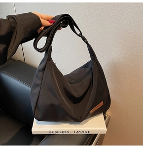 Detail of black crescent canvas tote bag with adjustable strap and leather logo patch