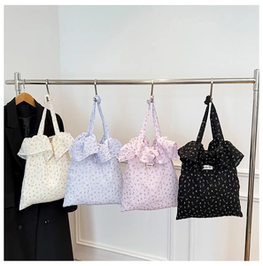 Détail de sacs fourre-tout en toile à fleurs plissés en coloris crème, bleu, rose et noir