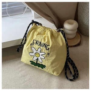 Detail der gelben Nylon-Beuteltasche mit Gänseblümchen-Stickerei und Kordelzug