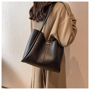 Detail showing high-capacity black leather tote bag with elegant metal buckle on side