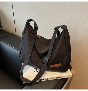 Detail of black nylon crescent hobo bag with adjustable strap and brown leather logo