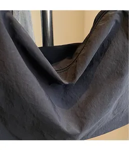 Close-up of lightweight black nylon tote bag showing waterproof texture and zipper detail
