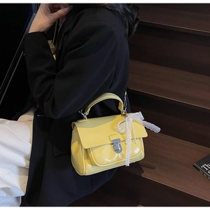 Chic yellow crossbody square bag featuring a silver twist lock and delicate lace bow charm
