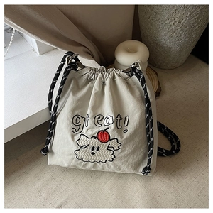Detail der beigen Nylon-Kordelzugtasche mit Hundestickerei und gewebtem Trageriemen