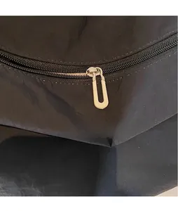 Detail of light gold polished U-shaped metal zipper puller on black canvas bag