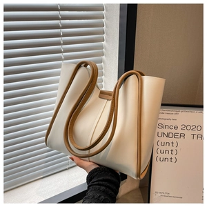 Detail view of cream white tote bag with brown straps showcasing high-quality PU leather texture