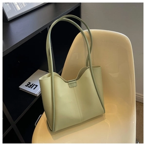 Detail of light green leather tote bag with magnetic closure on a modern chair