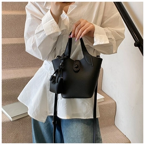 Detail of black lychee grain leather bucket bag with top handles and mini coin purse charm