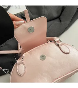 Detail of magnetic snap closure and pink PU leather on a half-moon shell handbag