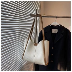 Detail of minimalist cream tote bag featuring contrast brown straps and trim on a hanger