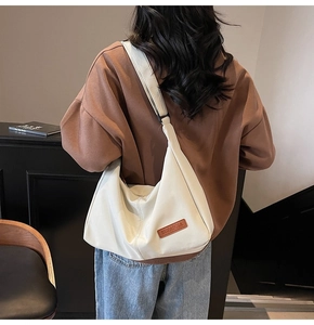 Close-up of the stylish white tote bag with a brown leather logo and wide shoulder strap
