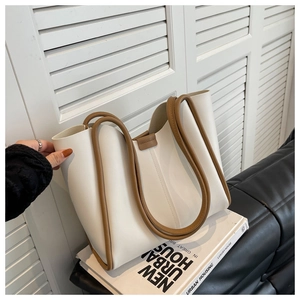 Detail of cream tote bag with brown handles placed on books by a shutter window