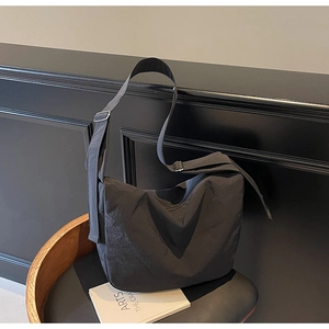 Detail of black nylon messenger bag featuring a wide adjustable strap and minimalist style