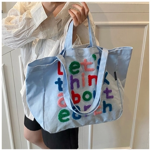 Detalle del bolso tote de lona azul claro con bordado colorido y correas de hombro cómodas