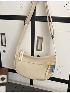 Minimalist beige canvas half-moon crossbody bag with adjustable nylon strap and zipper