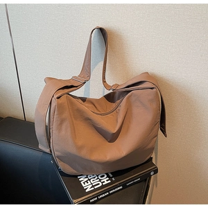 Detail of adjustable wide shoulder strap and silver buckle on brown nylon tote bag