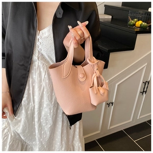 Close-up of pink bucket bag with litchi texture and matching mini pouch accessory