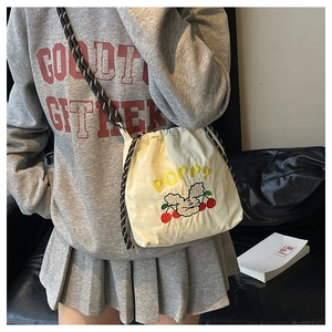 Detail der beigen Canvas-Beuteltasche mit Poppy-Stickerei und geflochtenem Schultergurt