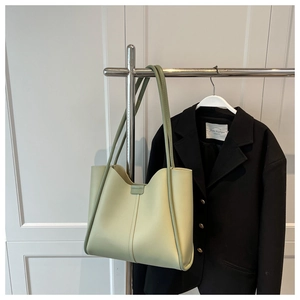 Minimalist light green leather tote bag with slim shoulder straps in a clean urban setting