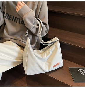Detailed view of white canvas tote bag with adjustable strap and leather logo patch