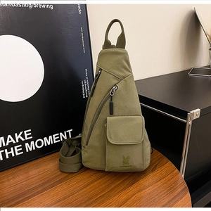 Detail of olive green canvas chest bag with rabbit logo on wooden table setting