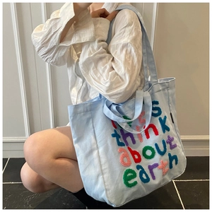 Primer plano de bolso tote azul claro con bordado colorido de Think about earth