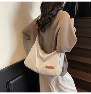 Detail of beige canvas tote bag showing side leather tag and thick cotton texture