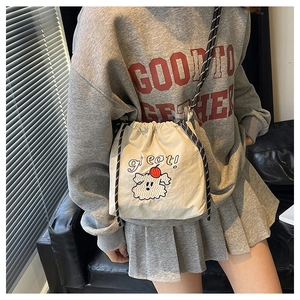 Detail der cremeweißen Tunnelzug-Beuteltasche mit Hundebestickung und gestreiftem Schultergurt