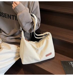Detail of a cream canvas tote bag with brown leather label on a rustic wood staircase