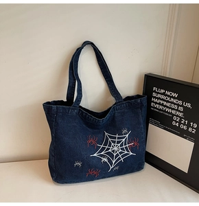 Detail of dark blue denim tote bag with spider web embroidery and red spider motifs