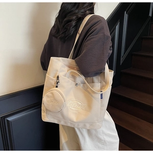 Sac cabas en toile blanc cassé avec un petit porte-monnaie rond utilisé dans un escalier