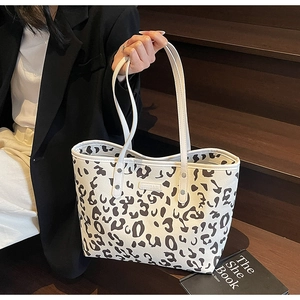 Detail van een witte tote bag met bruine koeienprint en witte lederen handvatten