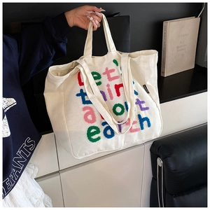Primer plano del bolso tote de lona con bordado de letras coloridas y asas resistentes